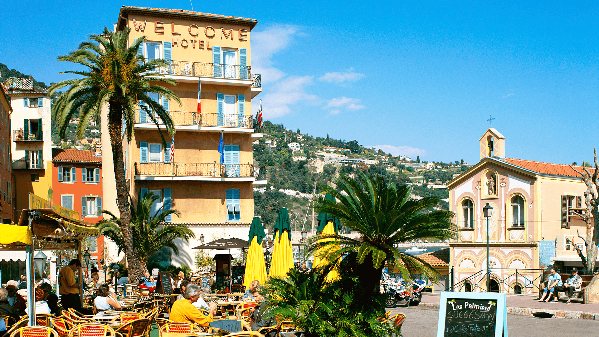 Sunny sidewalk café near a hillside village