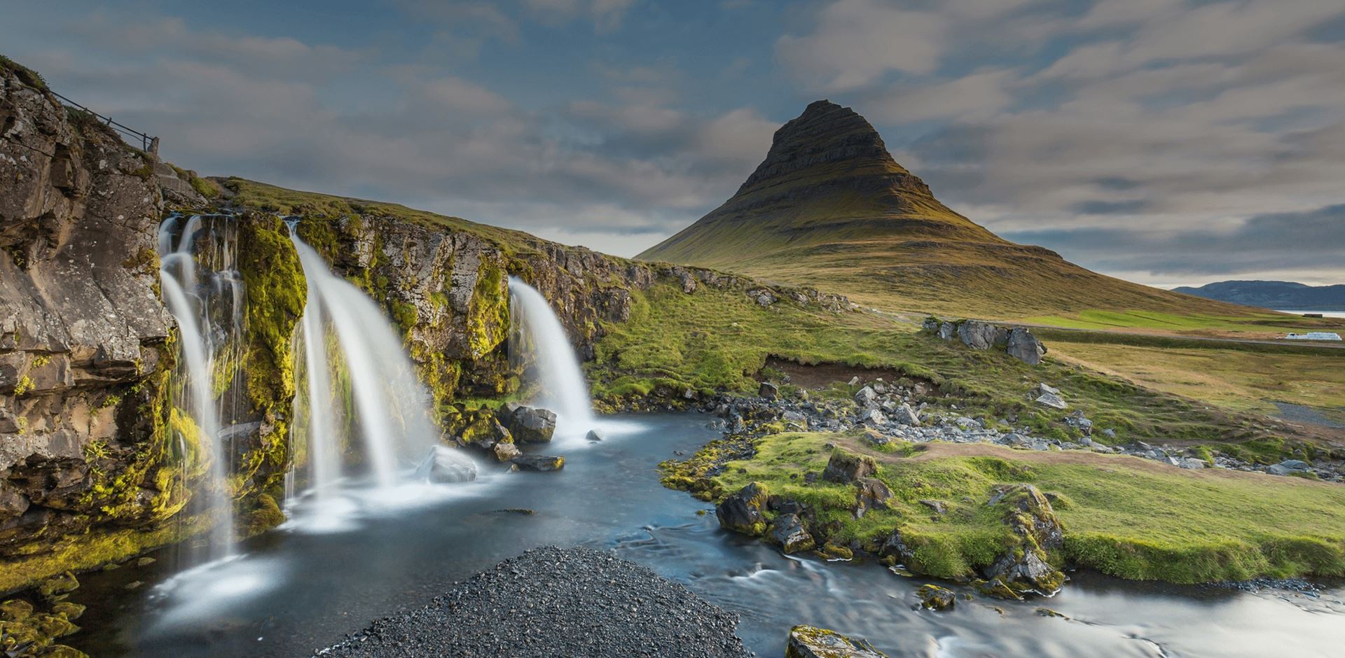  View of green landscape with mountain and waterfalls in Kirkjufellsfoss, Iceland 