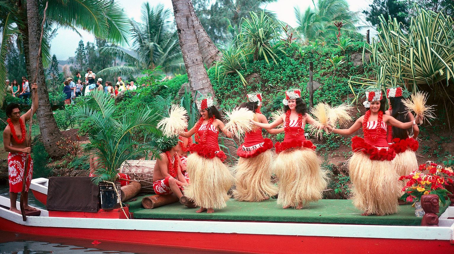 A group of smiling Hawaiian Hula dancers dancing.