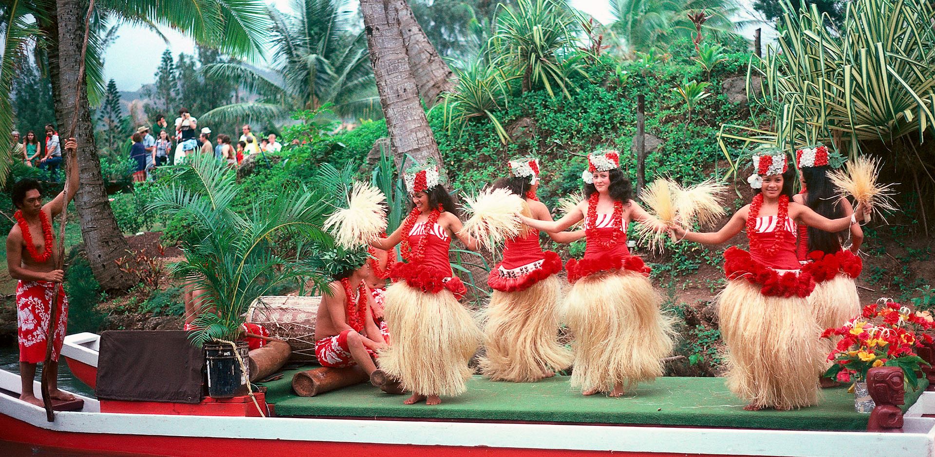 A group of smiling Hawaiian Hula dancers dancing.