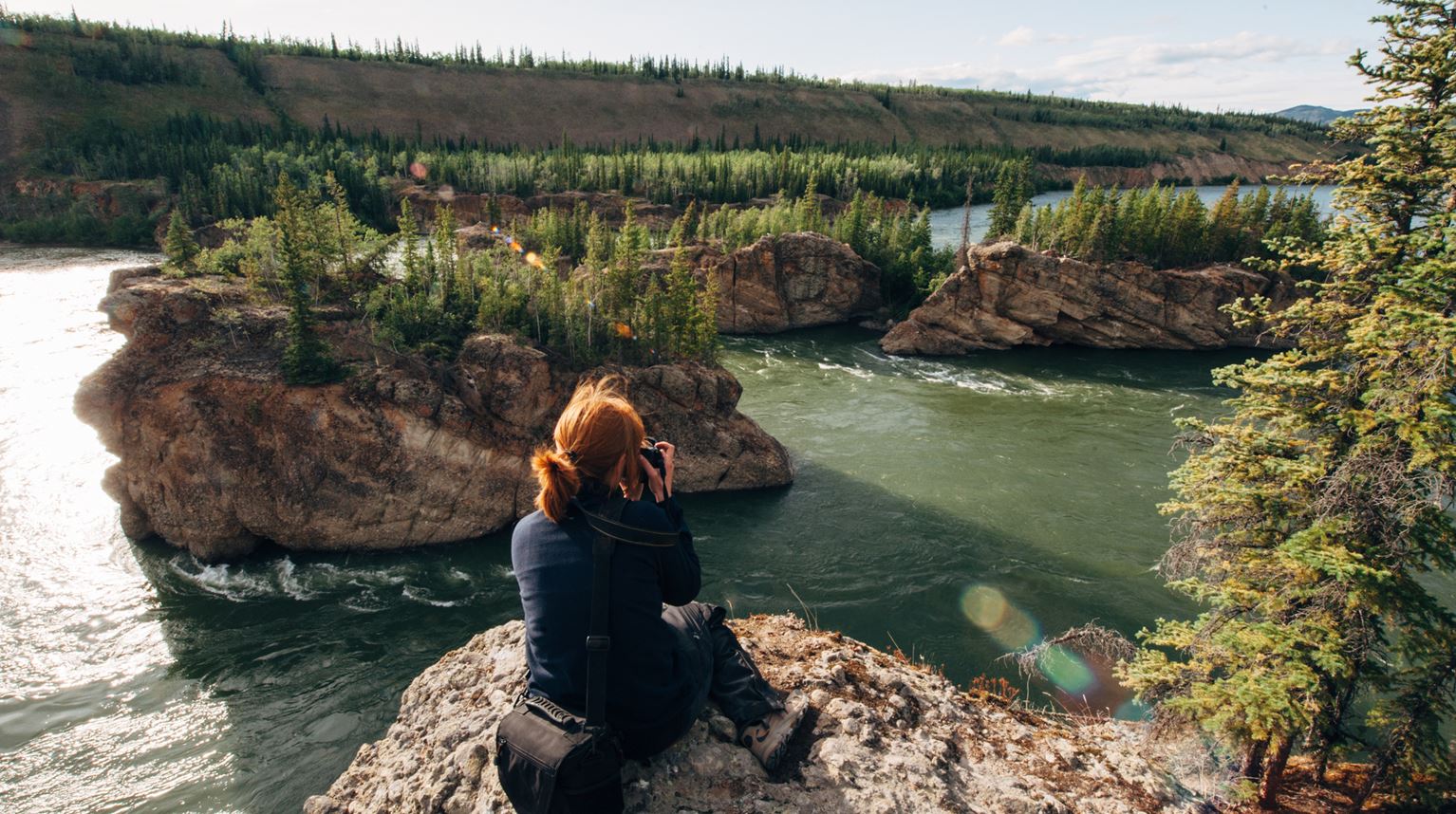 A Woman Sitting On Cliff by a River, Whitehorse, Canada 