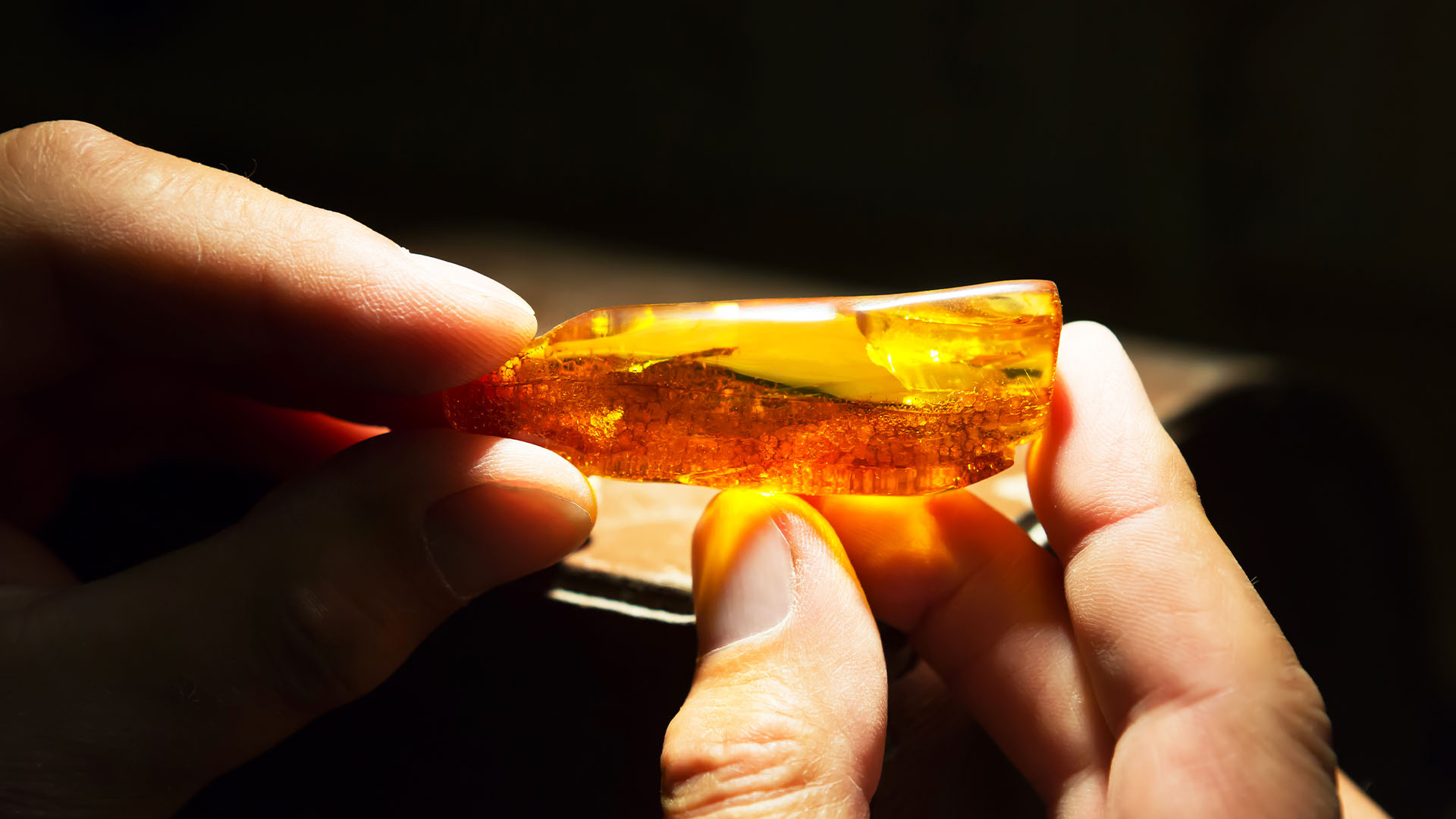 Close-up of a hand holding a backlit amber pendant