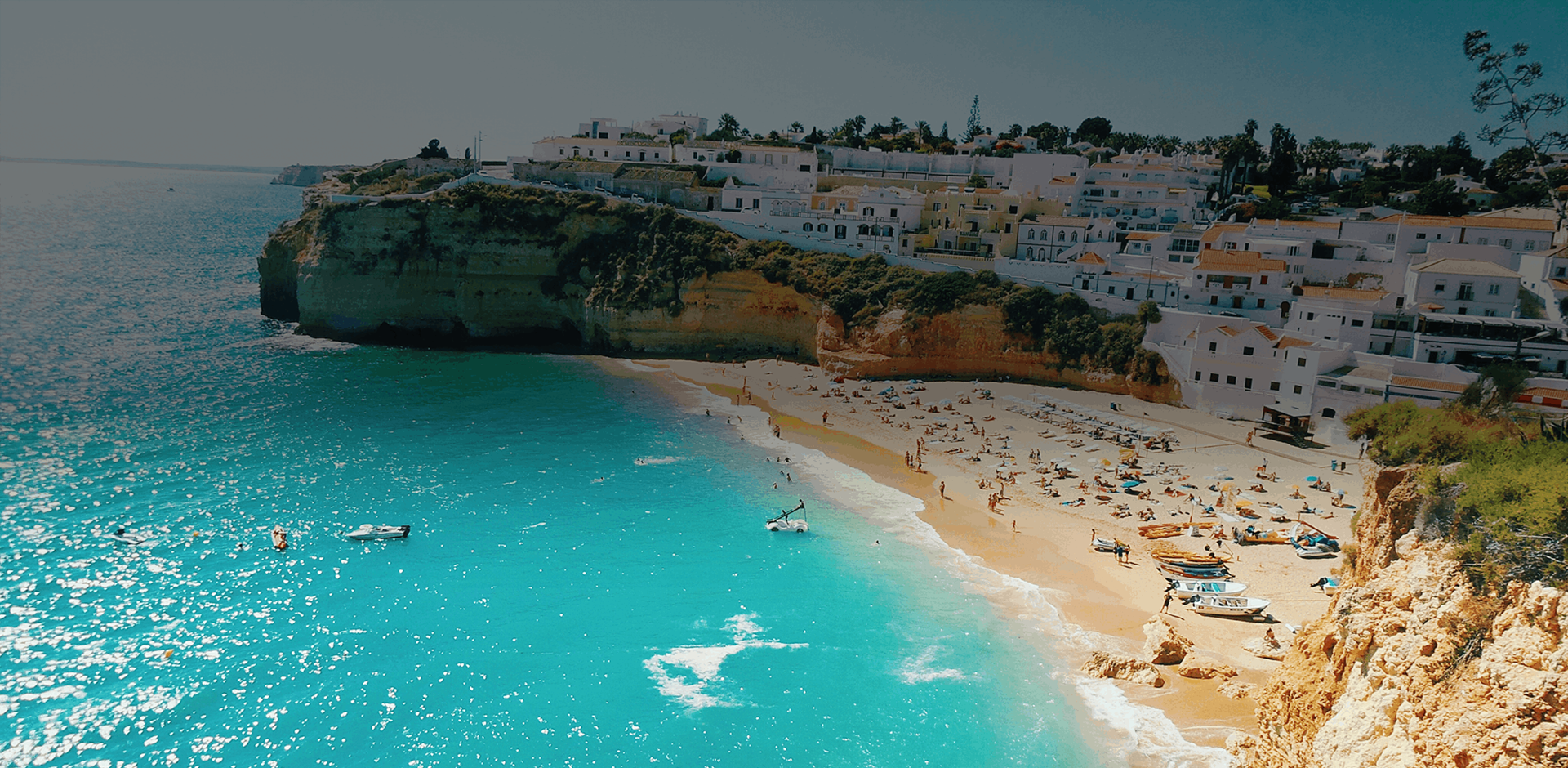 High angle view of beach with people swimming and sunbathing, ocean and houses at Carvoeiro, Portugal