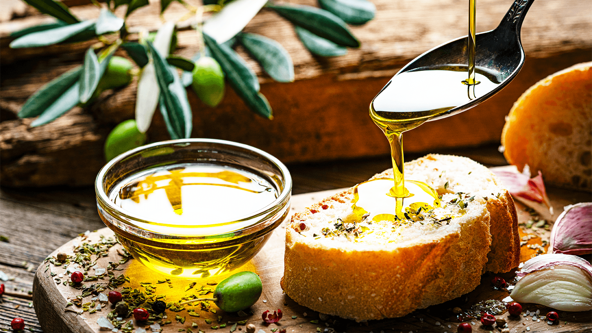 Olive oil pouring from spoon to a slice of bread