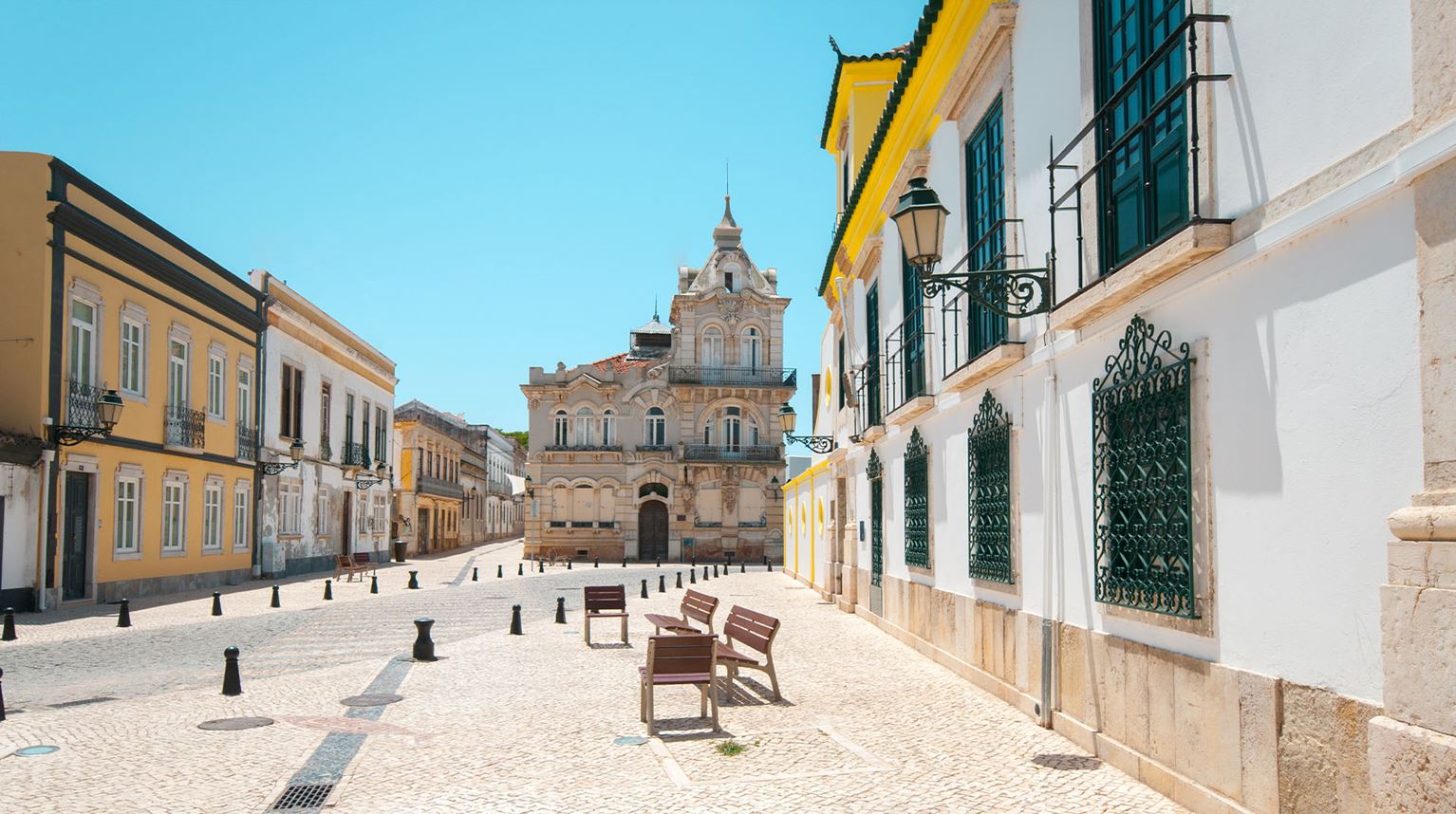 Sunny cobblestone street lined with stone buildings