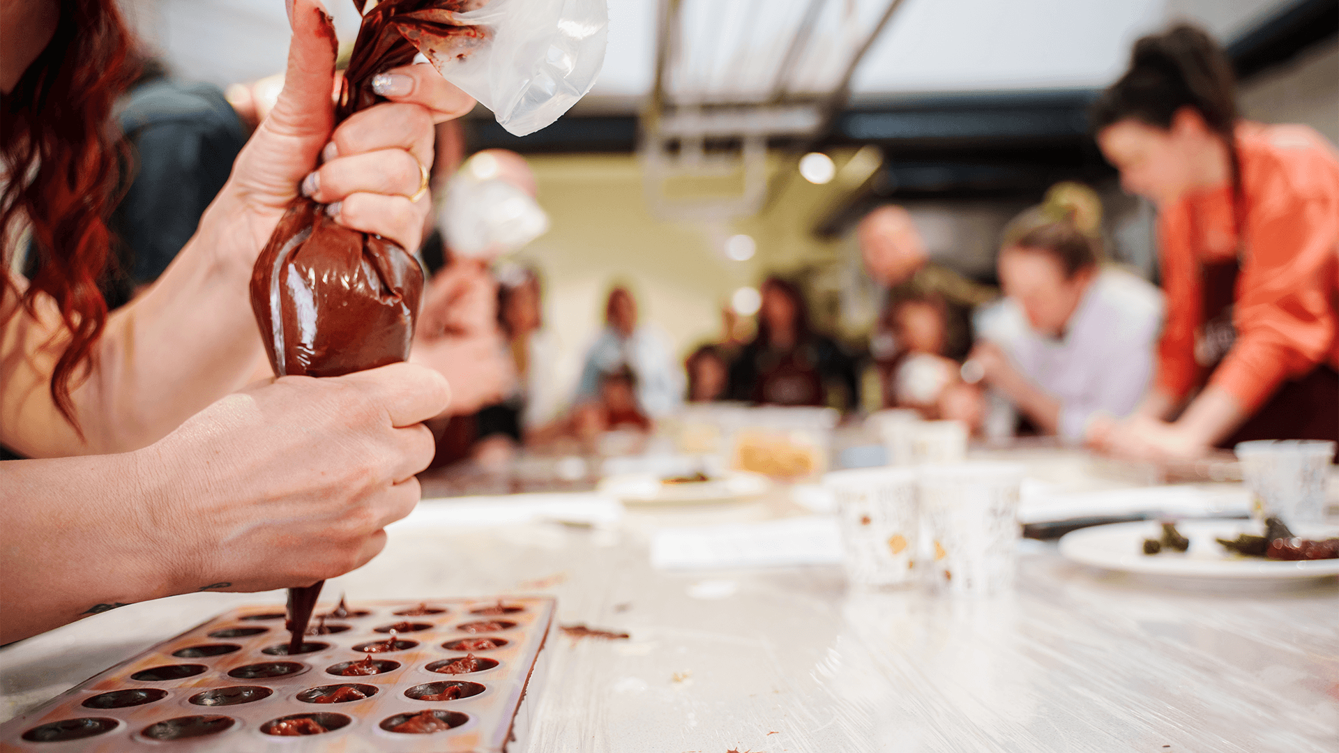 Hand piping liquid chocolate into a mold in a class