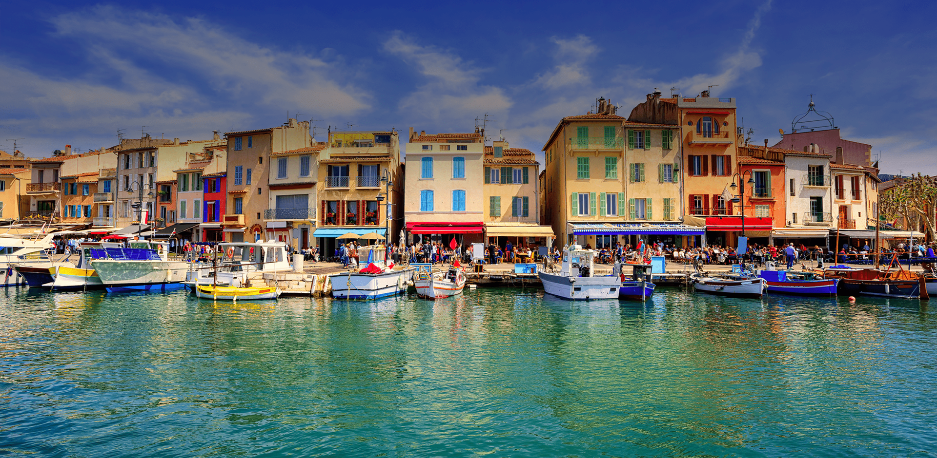 View from the water on Cassis old town port promenade with colourful small houses and boats, Provence, France