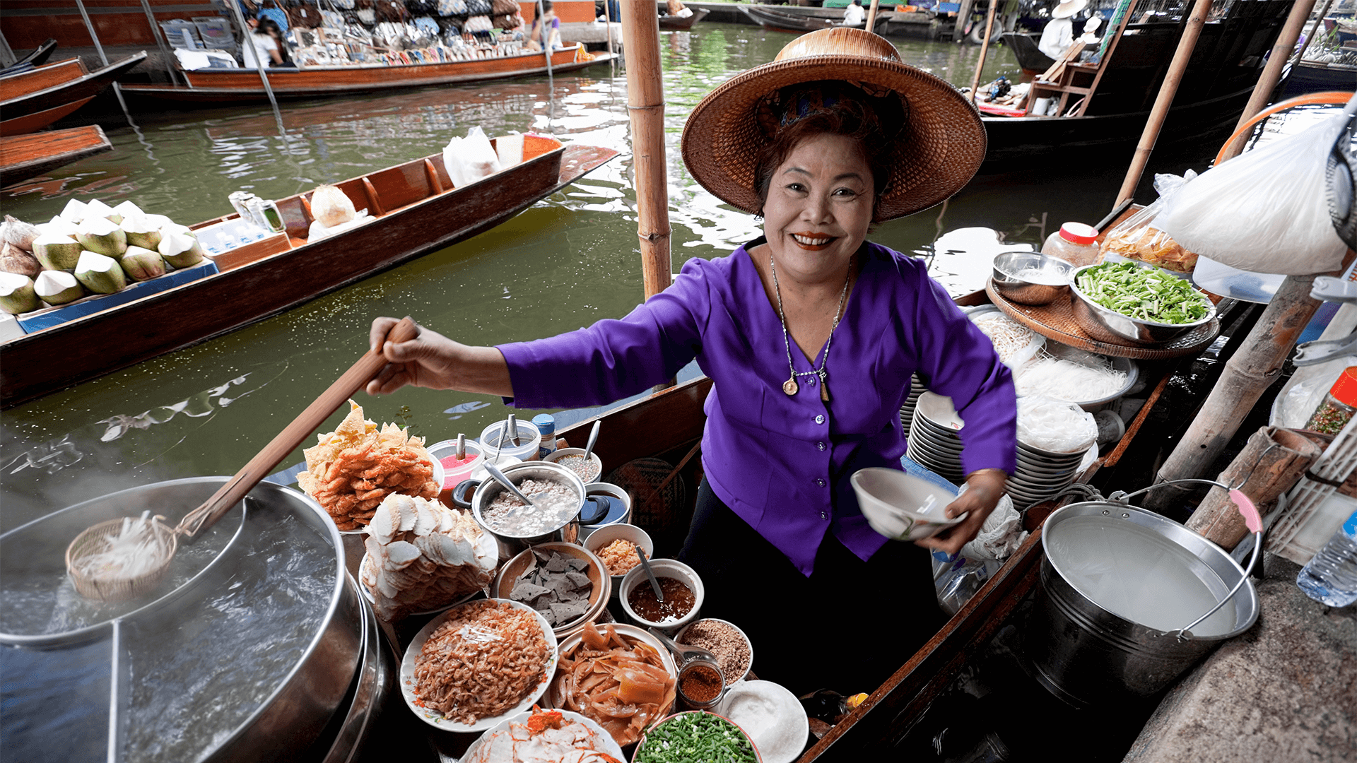 Floating market vendor preparing food from a boat. 