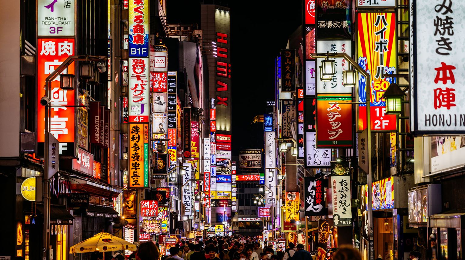 Bright neon signs line a pedestrian street at night