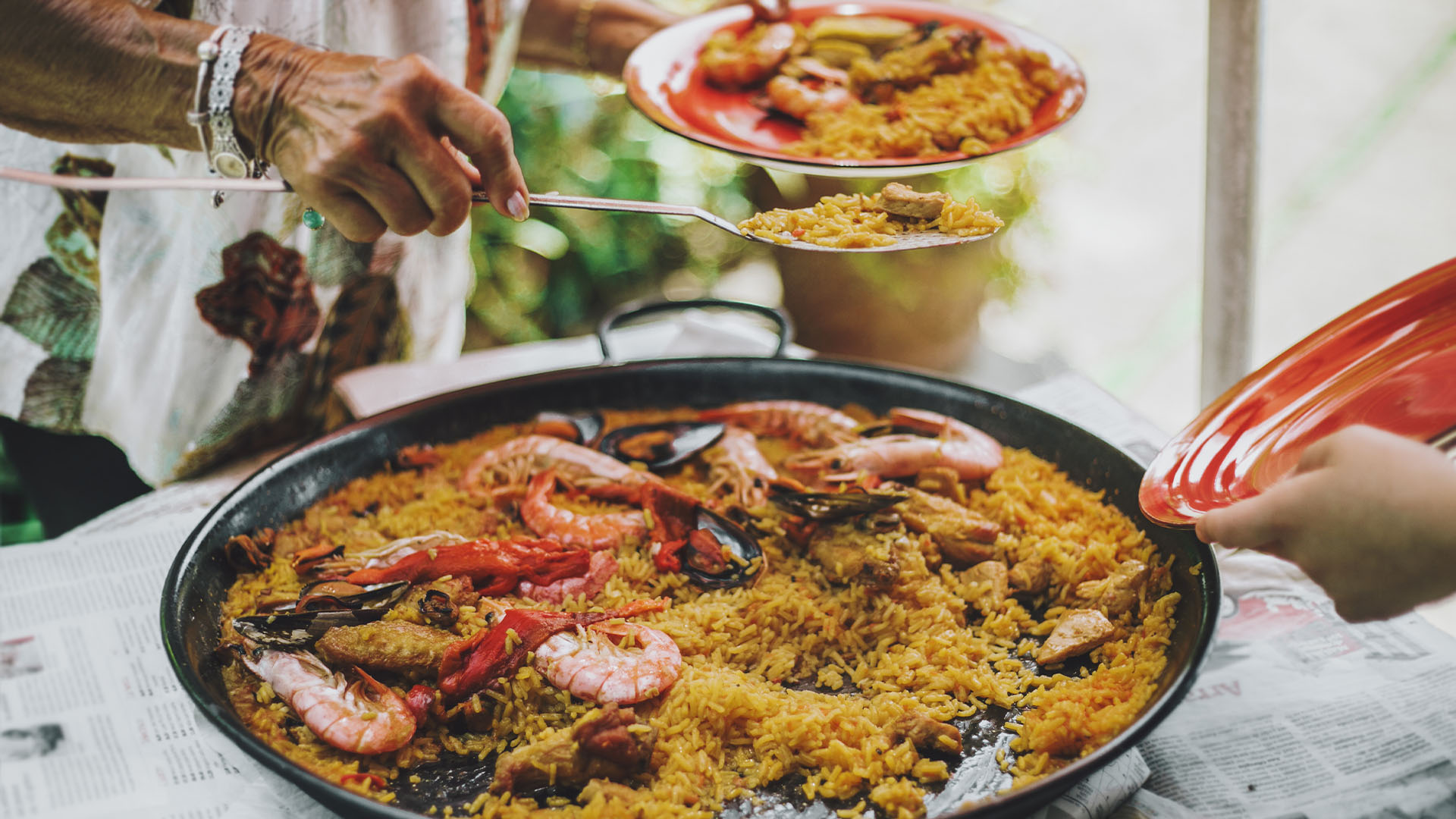 Woman serves seafood paella from a traditional pan