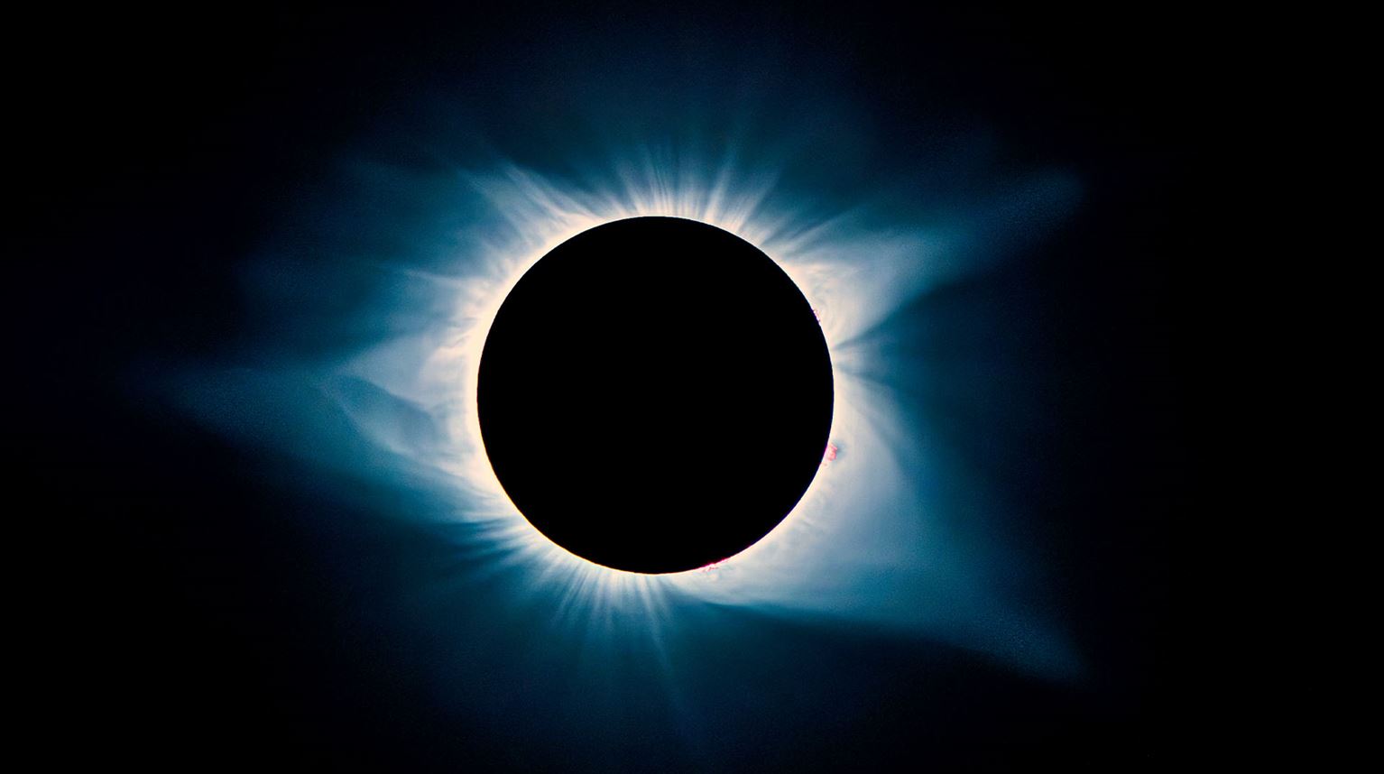 A total solar eclipse in a dark sky with solar flares.