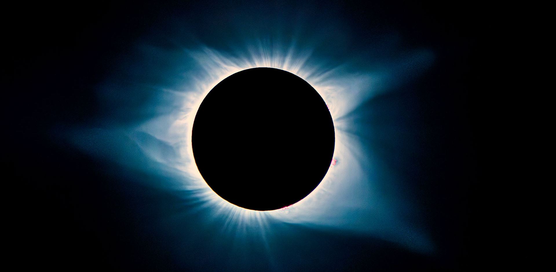 A total solar eclipse in a dark sky with solar flares.