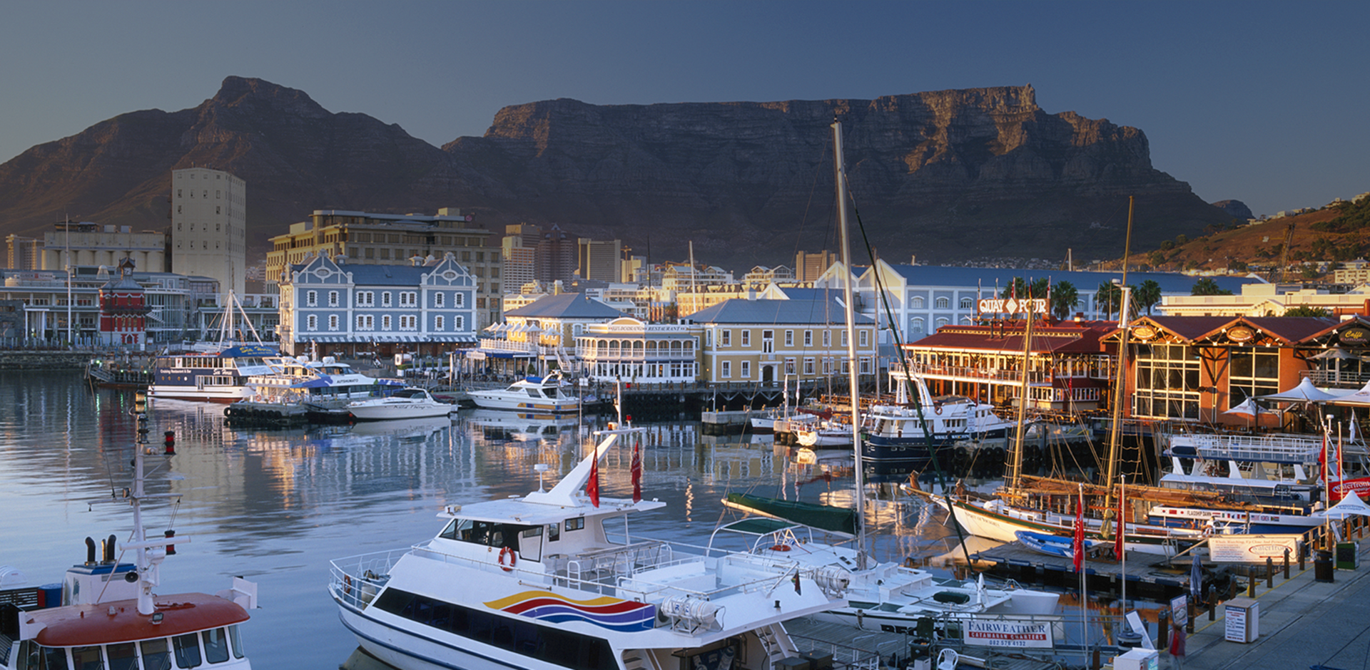 Waterfront town with boats in harbor with Table Mountain in background, South Africa. 