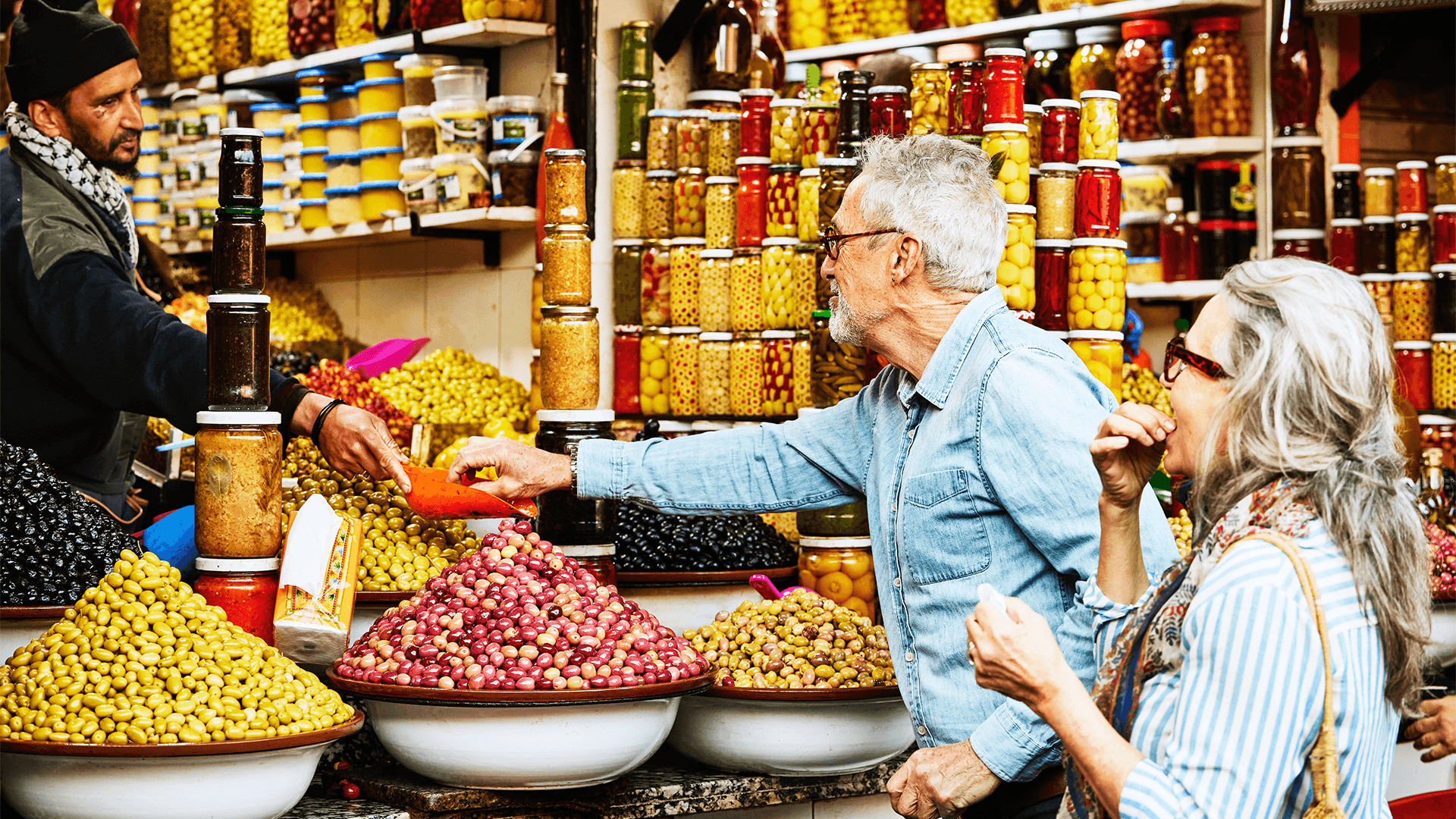 A couple shops for olives at a Marrakech market stand