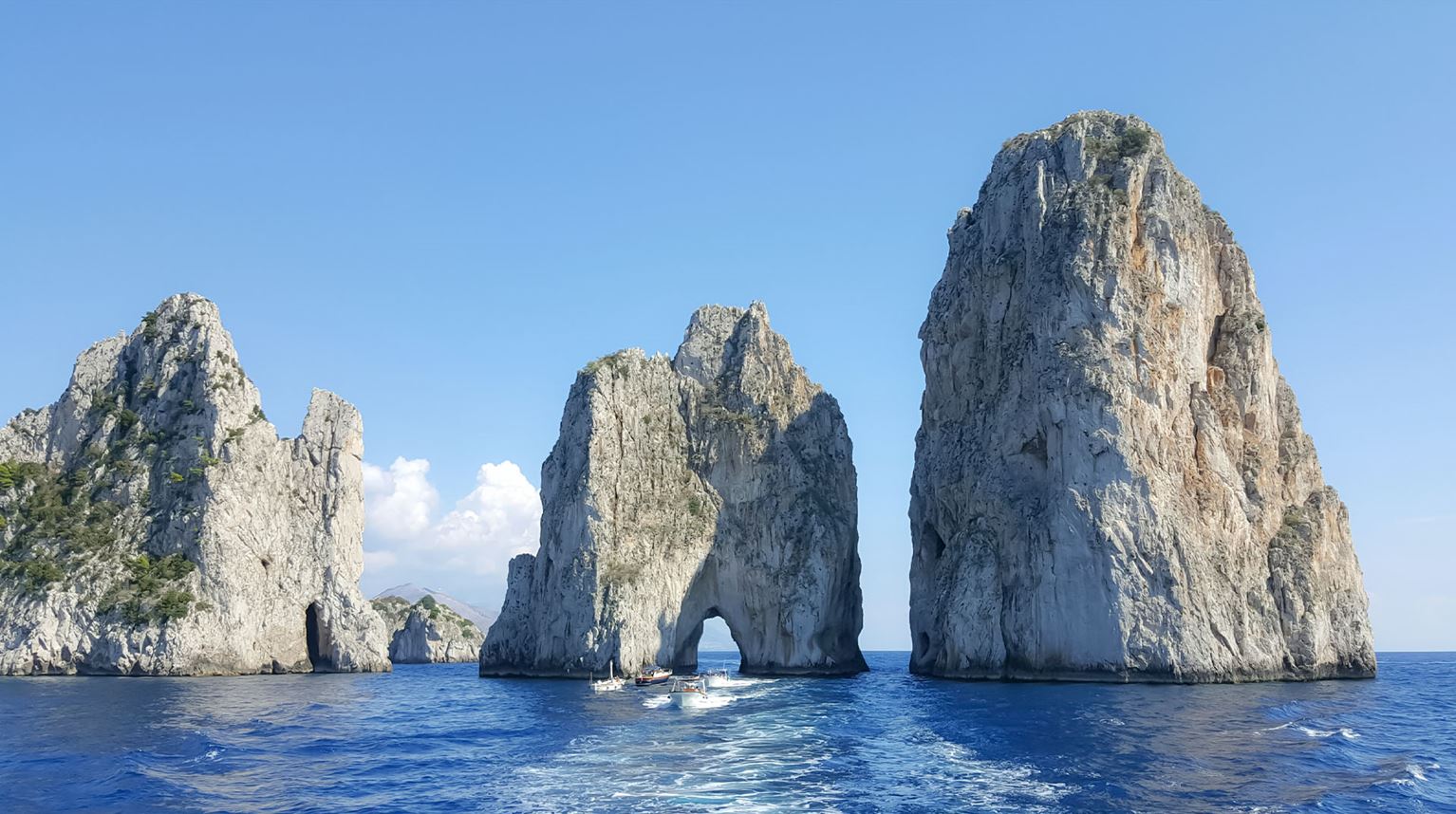 Towering rock formations rising from a bright blue sea. 