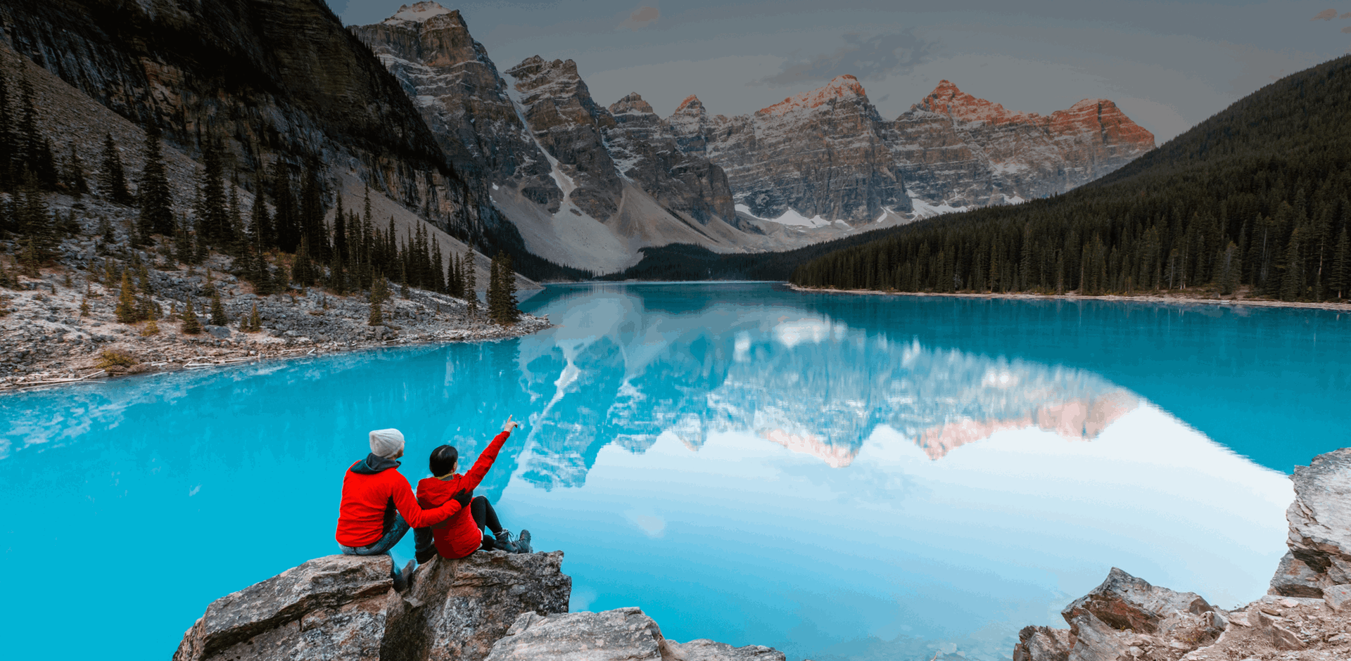 Couple looking at piercing blue Moraine lake and mountains, Banff, Alberta, Canada.
