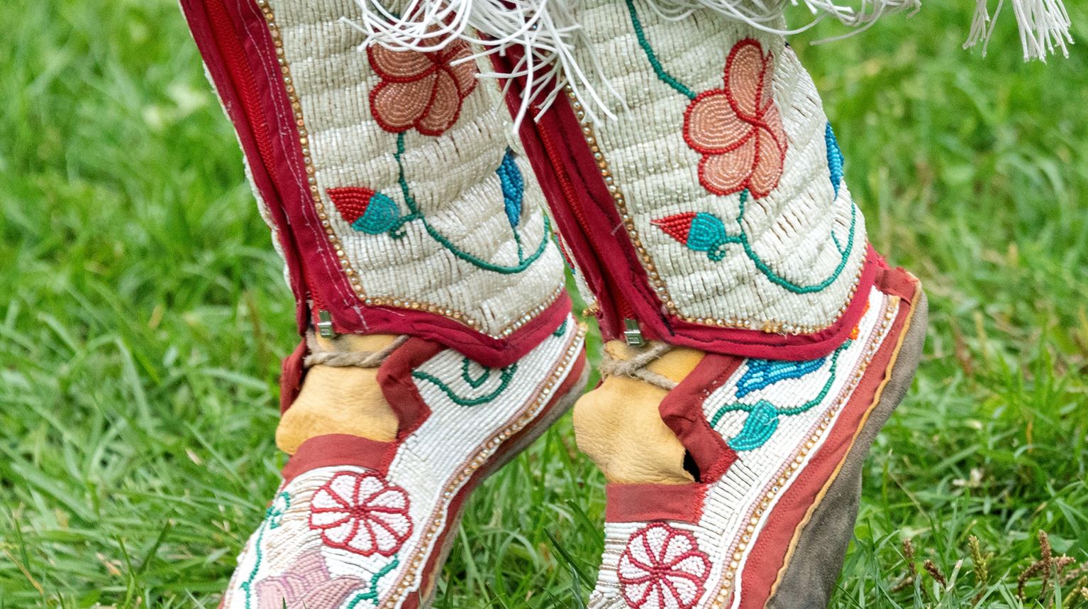 Canadian First Nations traditional colorful shoes on a dancer in a grass. 