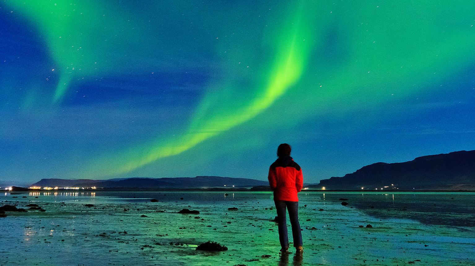 Man watching Aurora Borealis in Borgarnes, Iceland