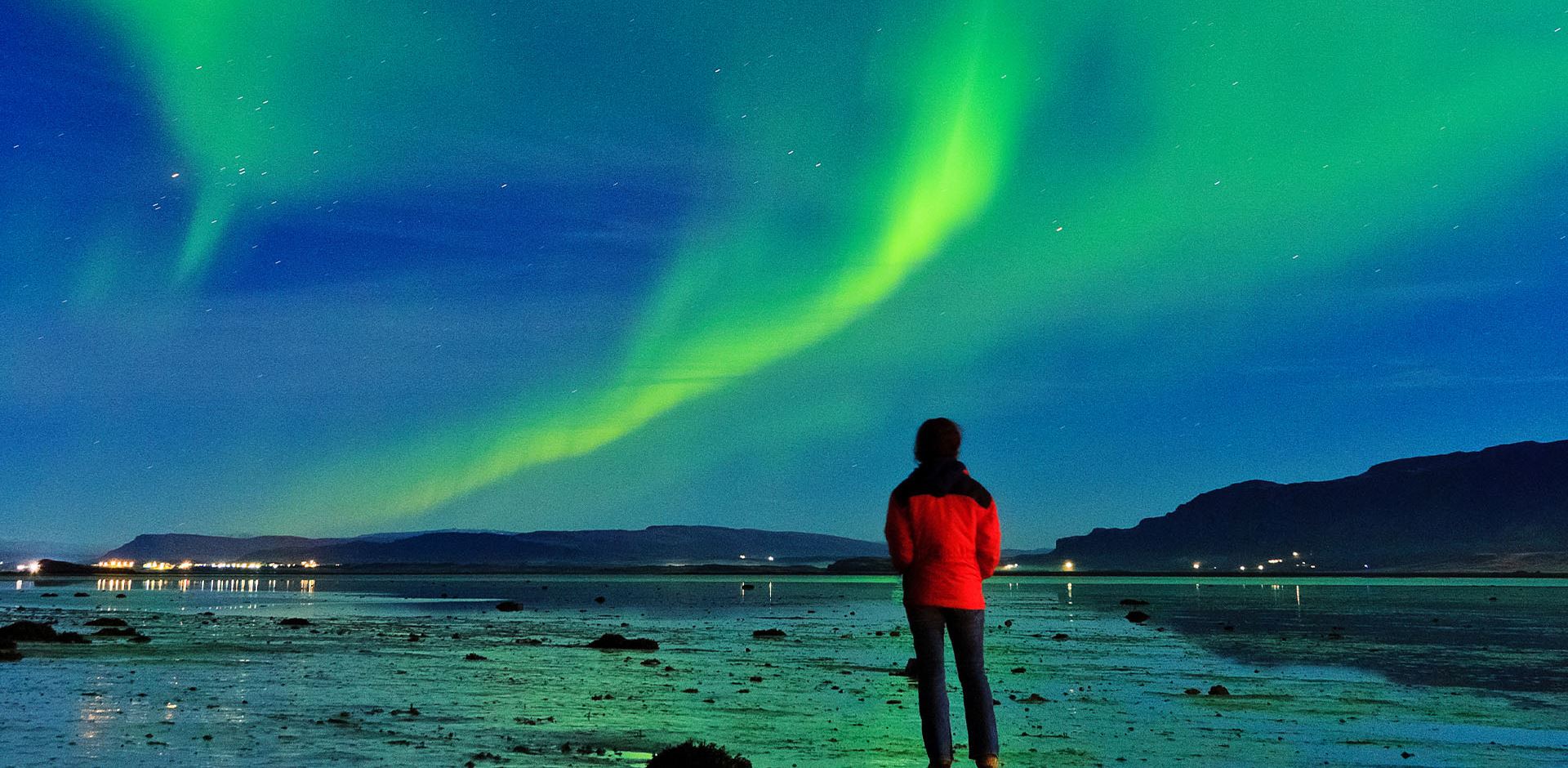 Man watching Aurora Borealis in Borgarnes, Iceland