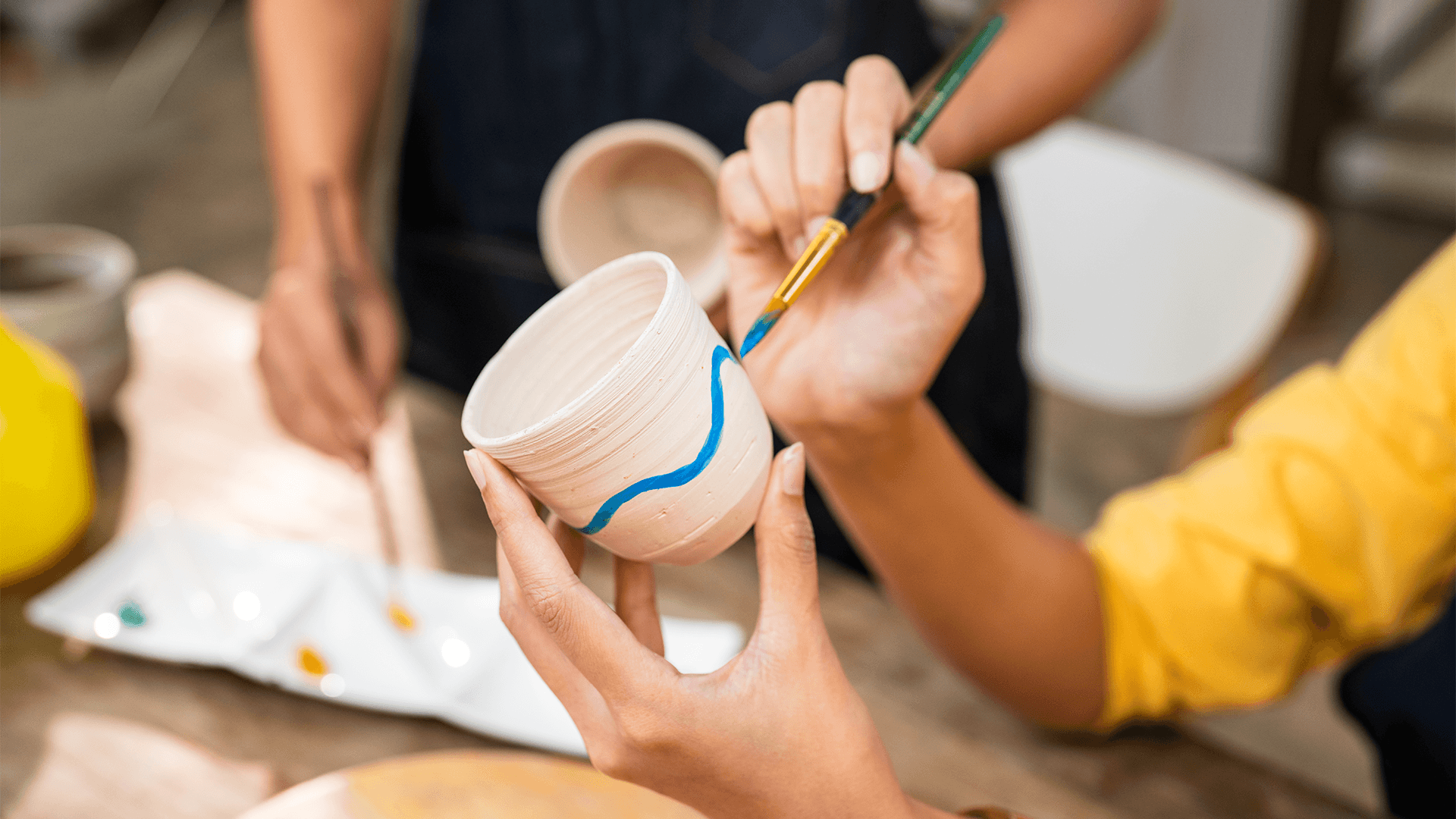 Close up of a woman painting a ceramic cup in a class