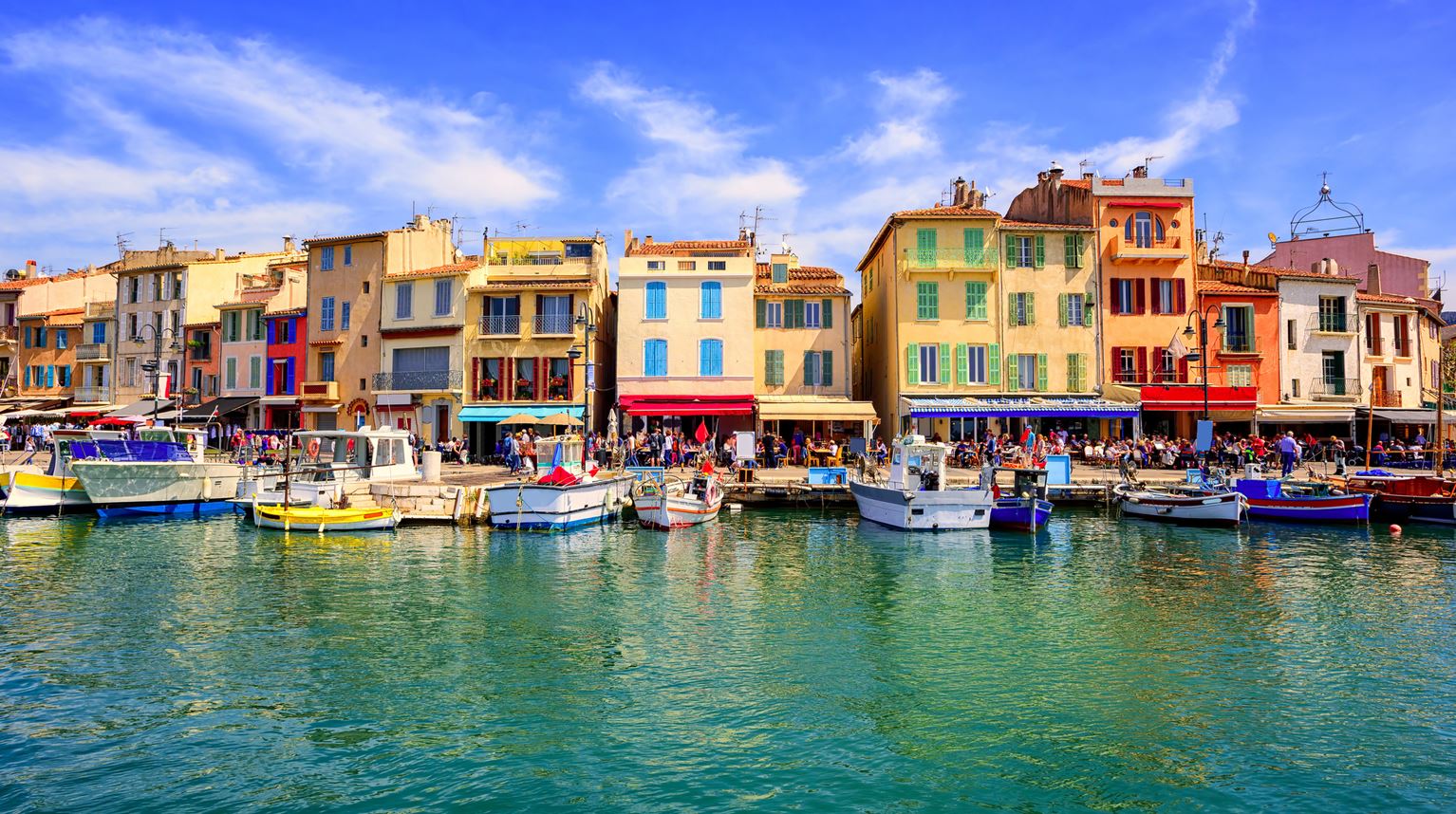View from the water on Cassis old town port promenade with small houses and boats, Provence, France