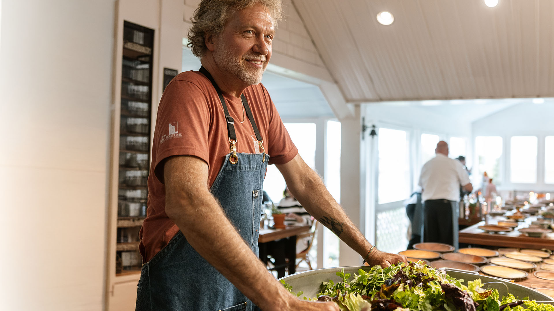 Chef Michael Smith smiles next to a platter of food