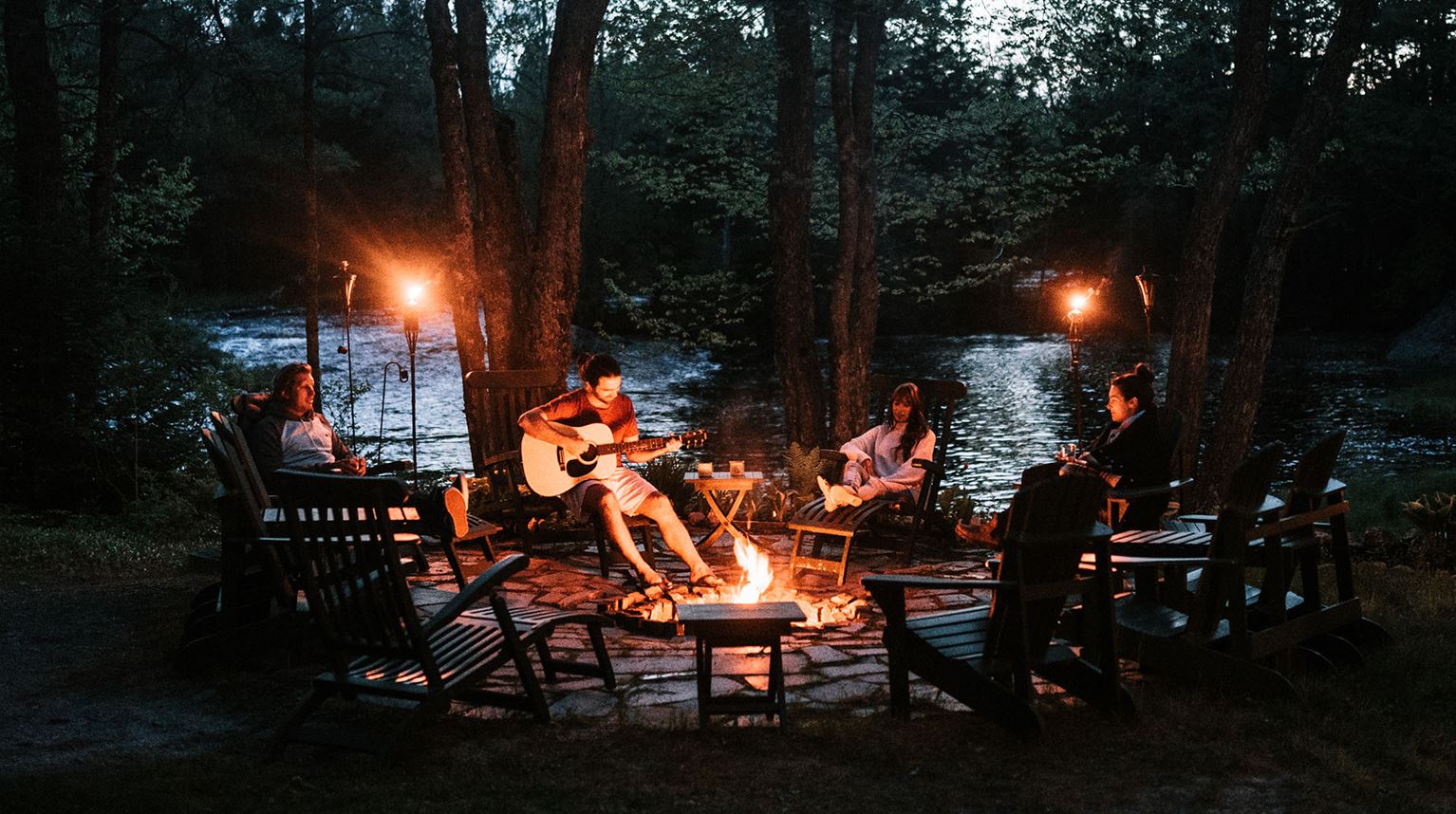 A group of people by a campfire at Trout Point Lodge, Nova Scotia