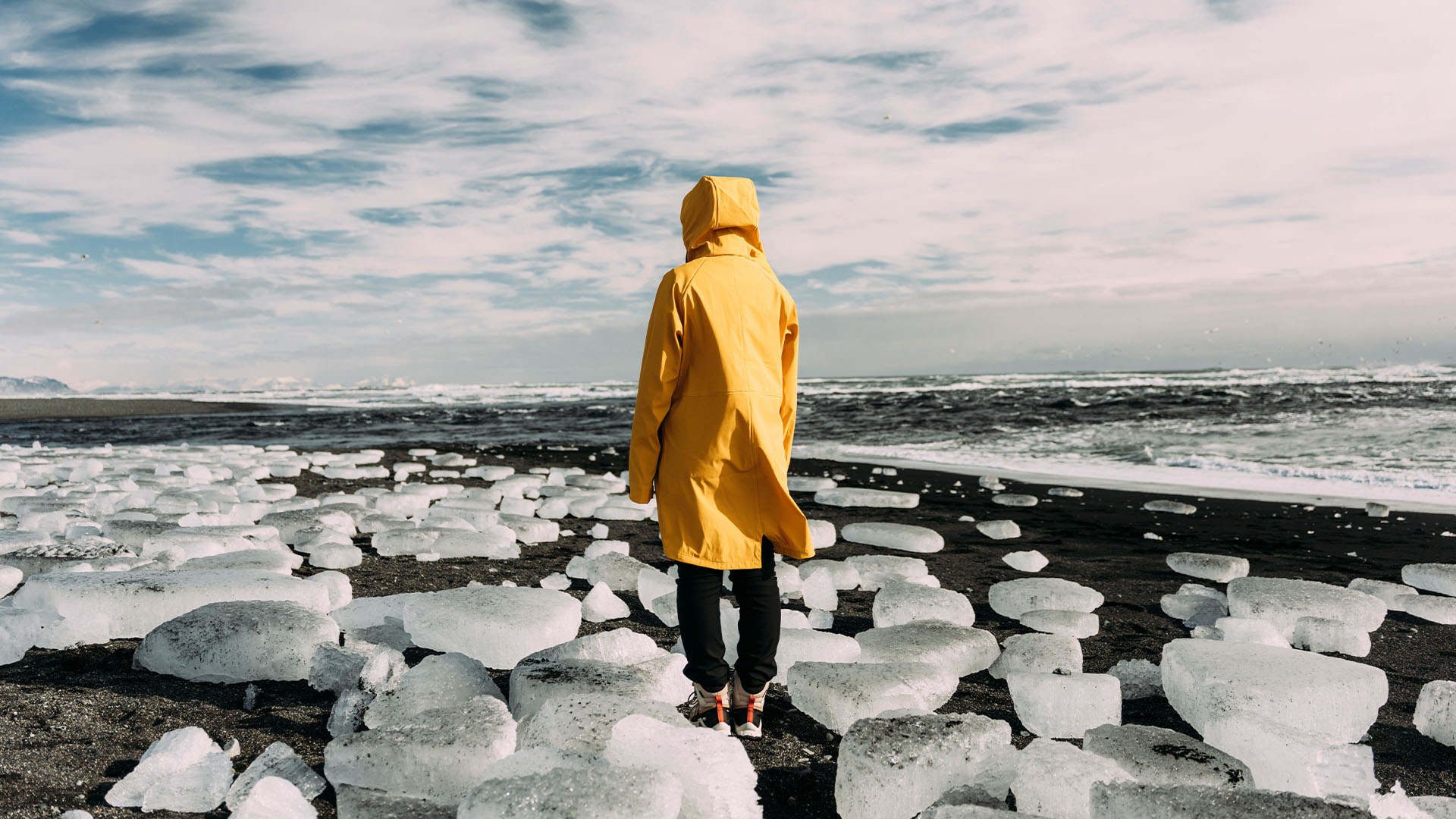 Person on black sand and ice blocks on Diamond Beach