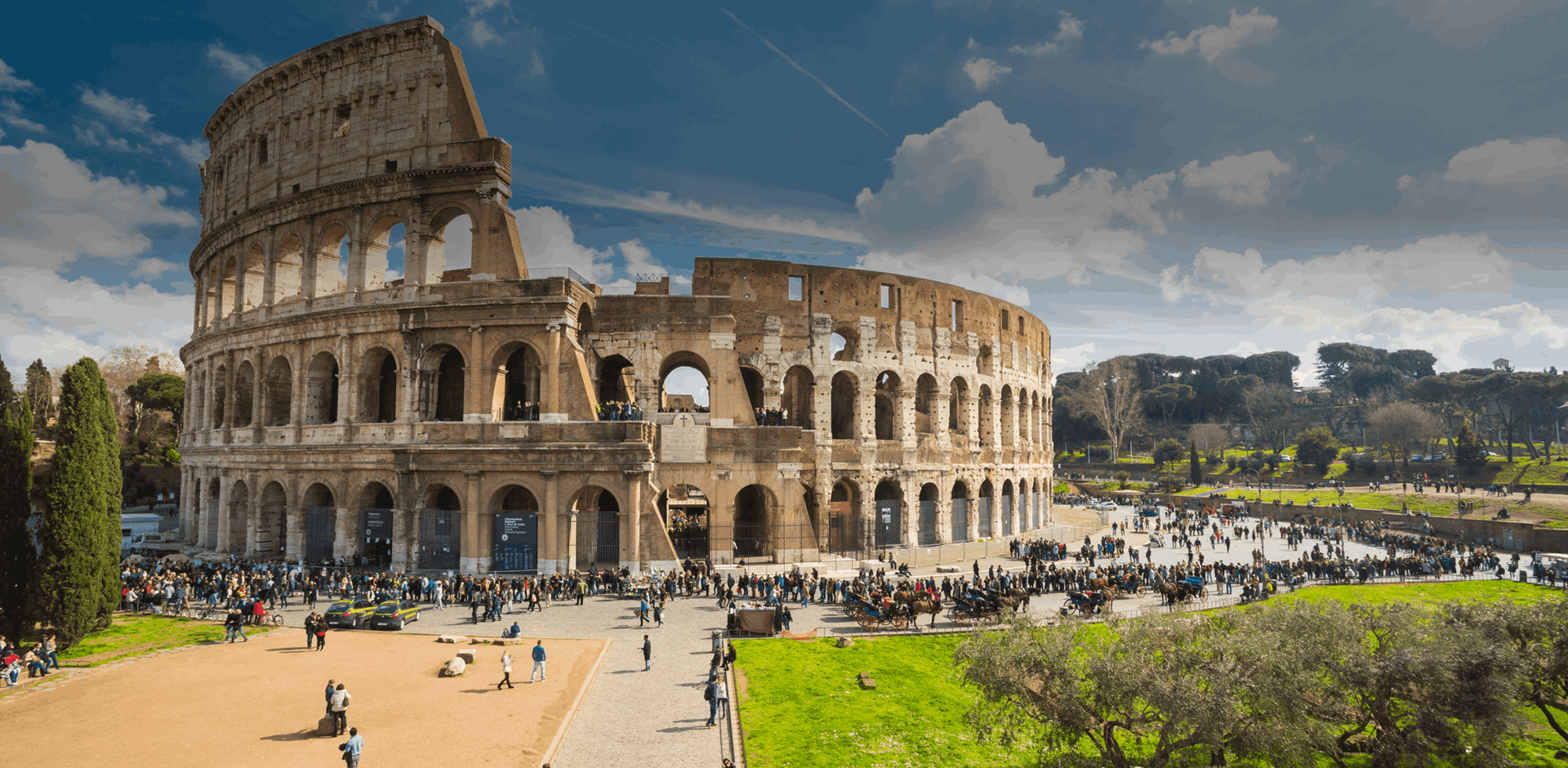 View of the Colosseum and the area around with many tourists walking and enjoying the day, Rome, Italy. 