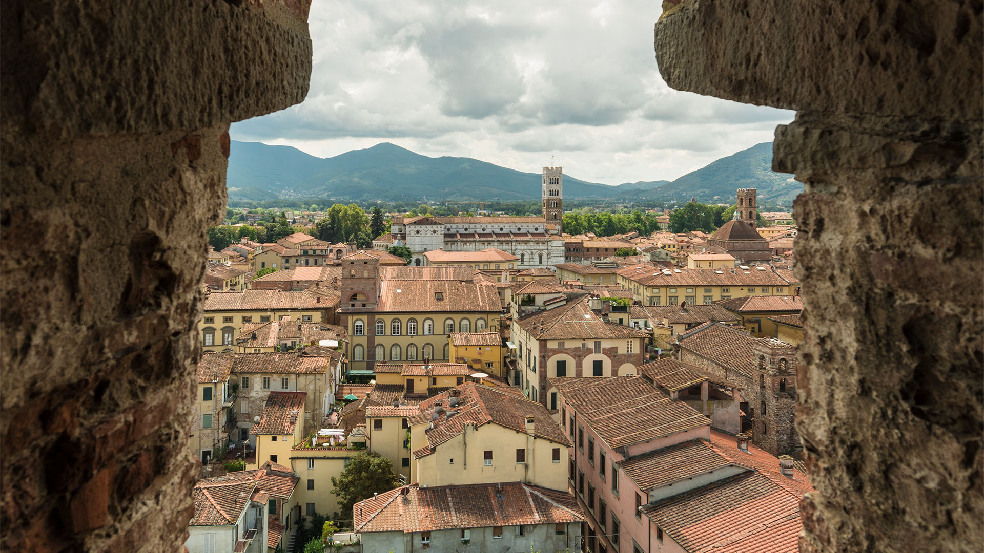 View over Lucca through a medieval stone tower opening