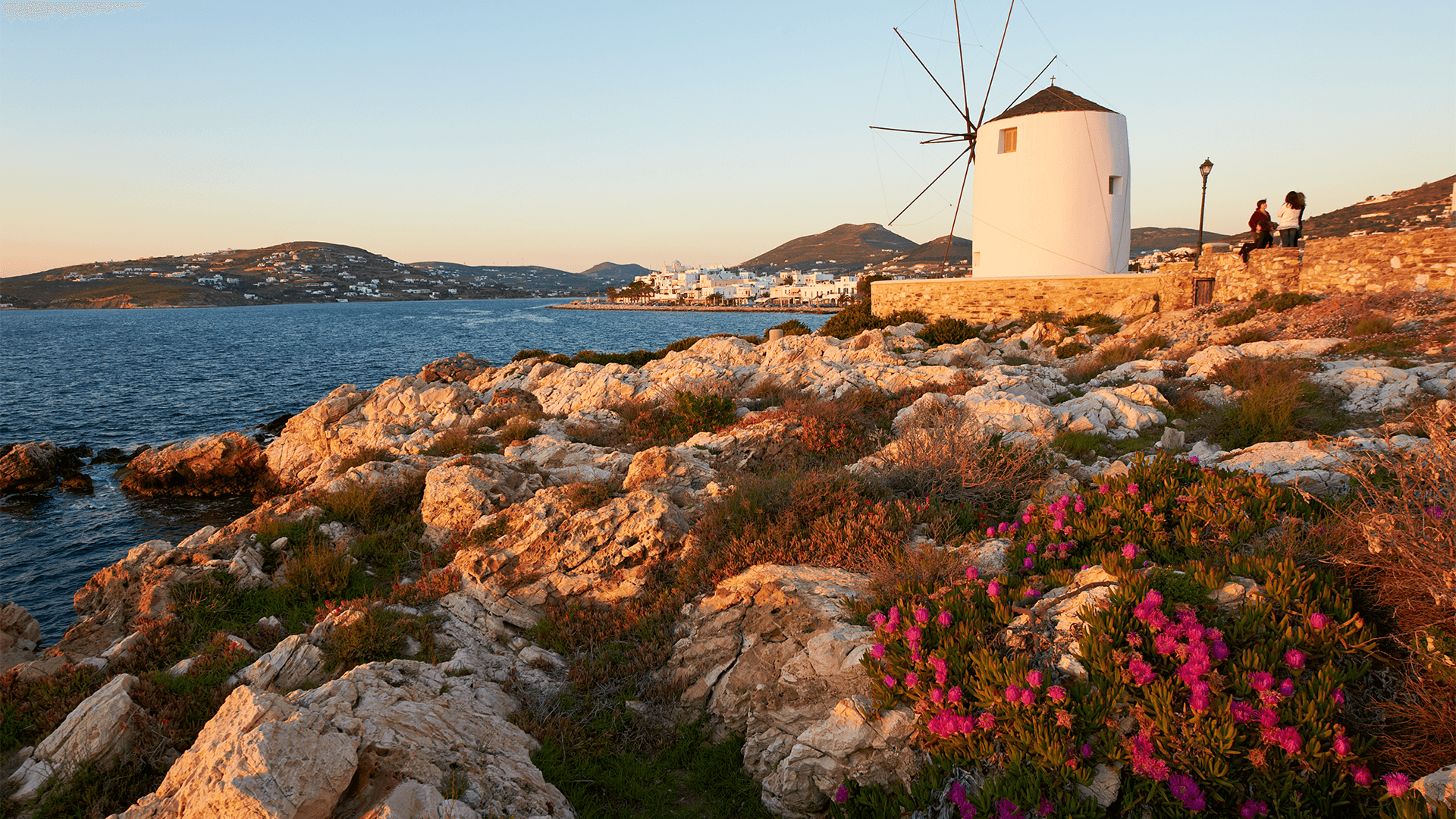 Traditional windmill sits on a rocky harbour wall