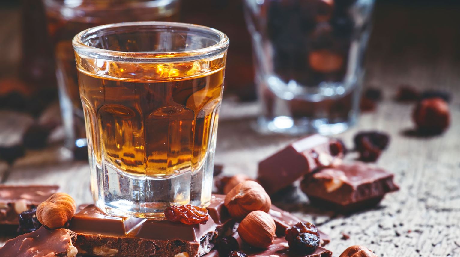 Glass of whisky on counter with nuts and chocolate