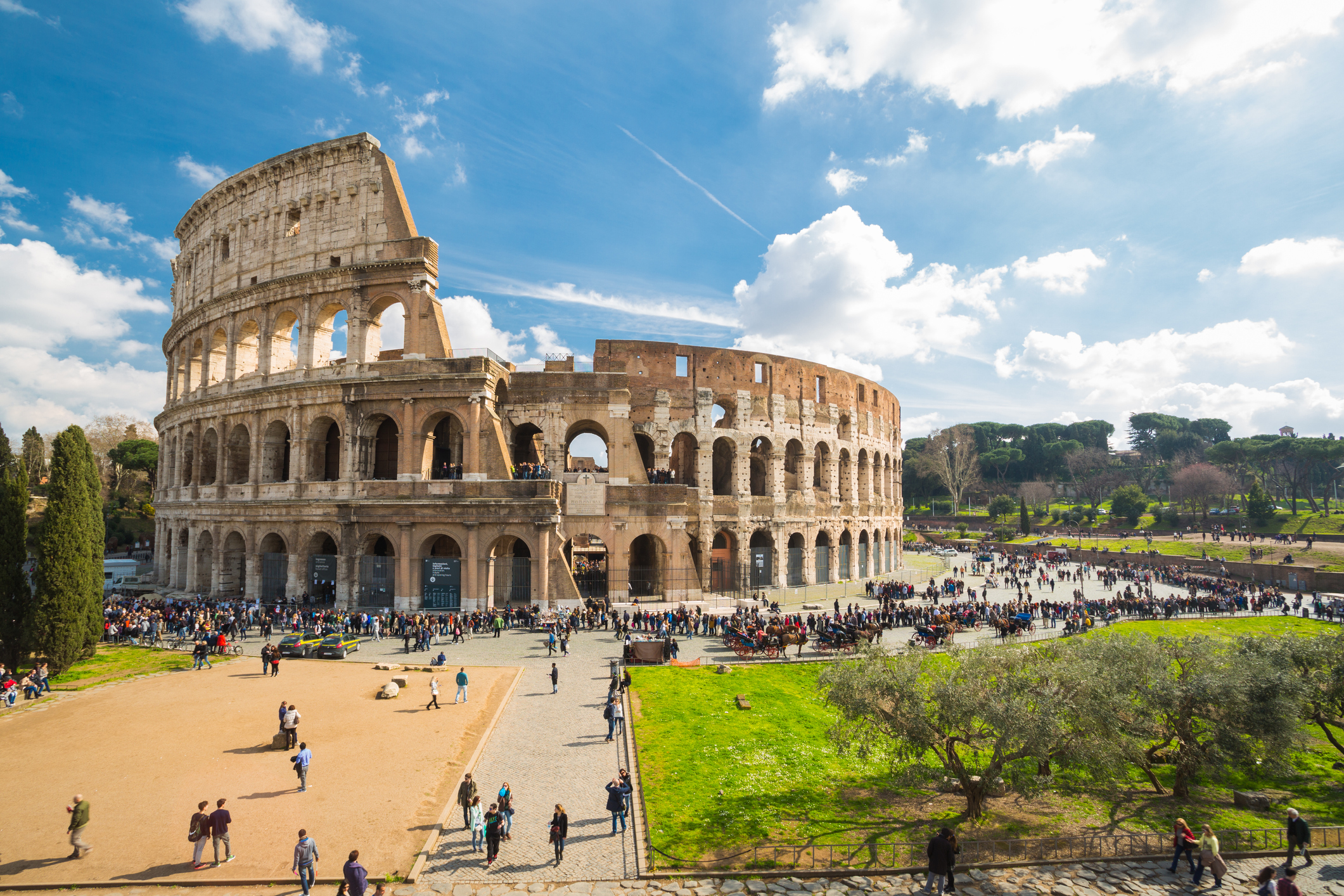 View of the Colosseum and the area around with many tourists walking and enjoying the day, Rome, Italy. 