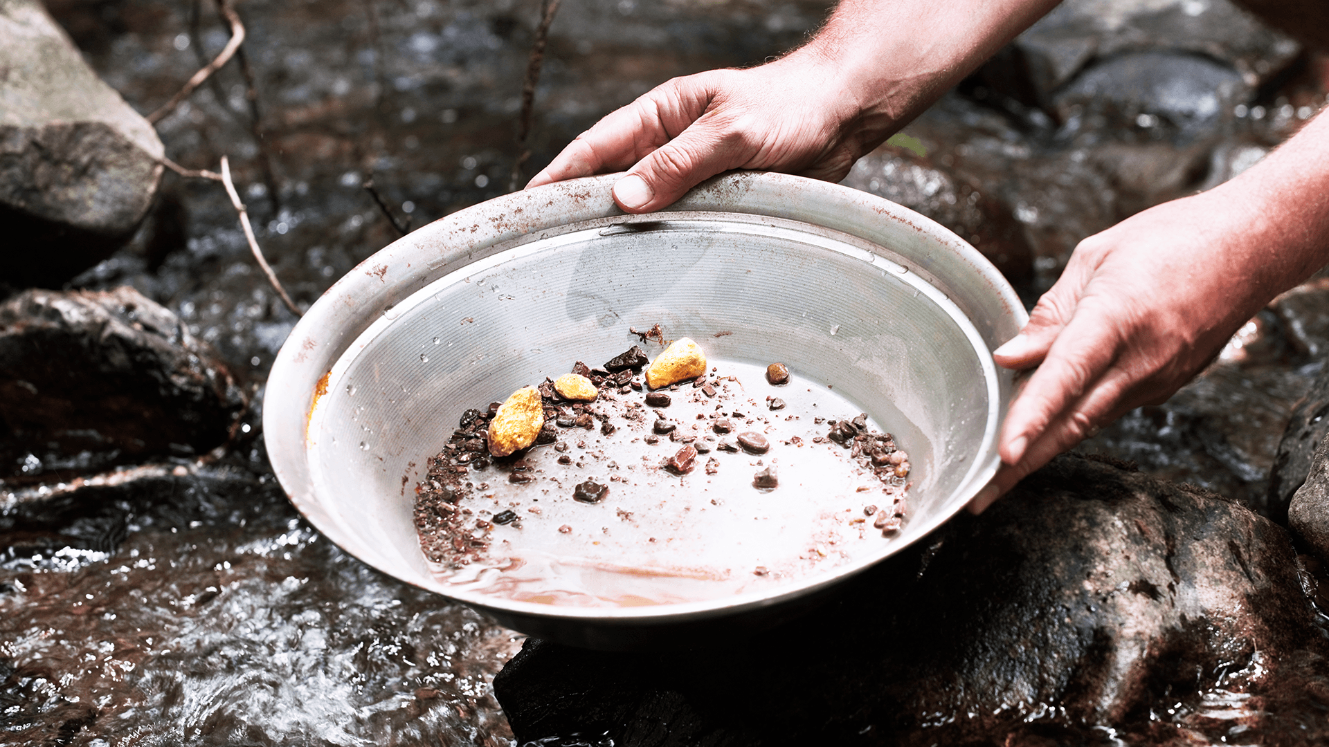 Hands panning for gold in a Yukon creek