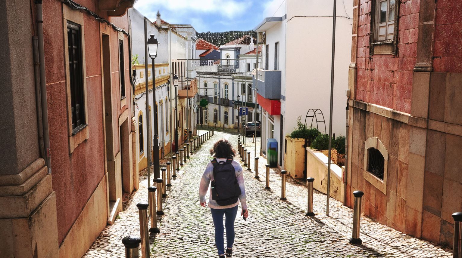 Woman walking down a colourful cobblestone street