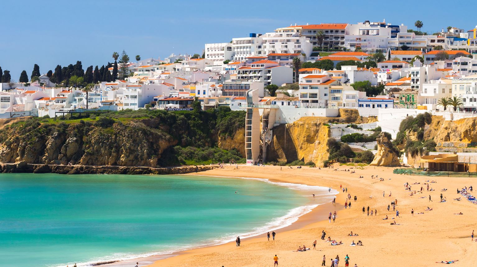 Aeriel view of Albufeira Beach in Algarve, Portugal showing turquoise water with people on the beach