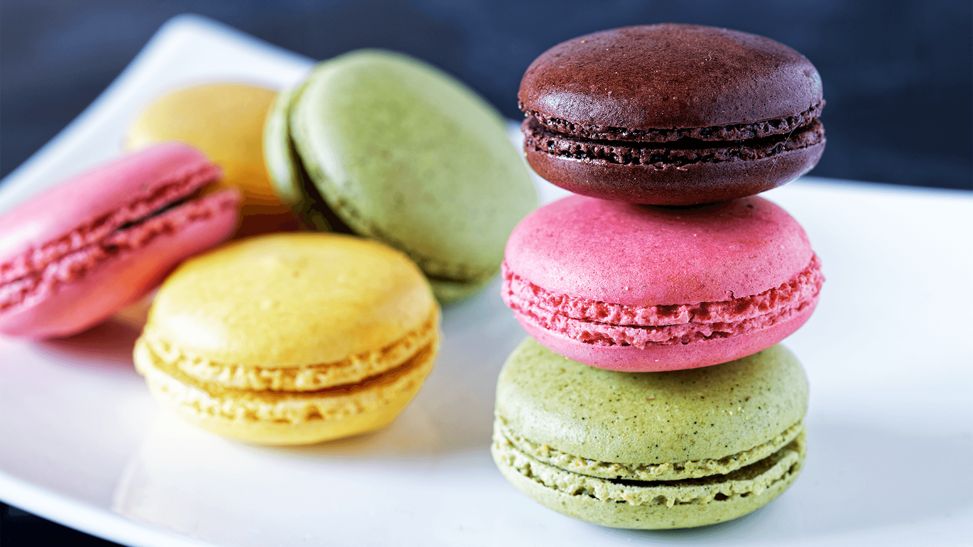 A white plate stacked with colourful macaron cookies