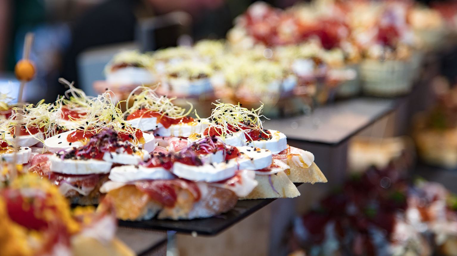 Close-up of pintxos stacked on plates at a bar counter